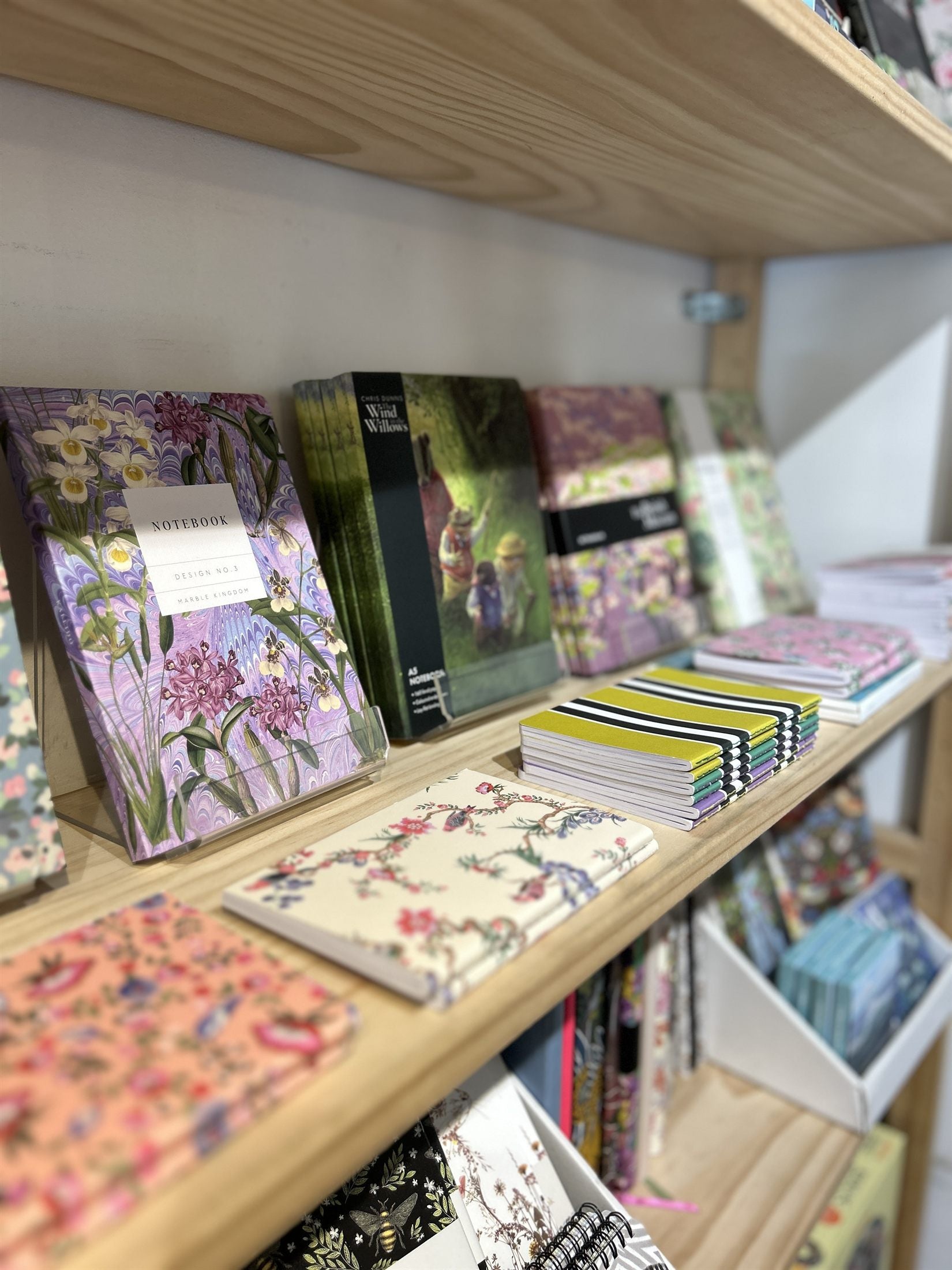 Marbled and floral notebooks on a light wood shelf